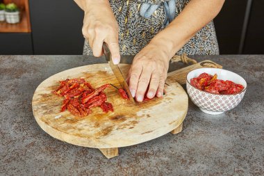 Mutfak ortamında ahşap kesim tahtalarında mozarella, sert peynir ve yeşil soğan dilimleyen ellerin yakın plan görüntüleri..