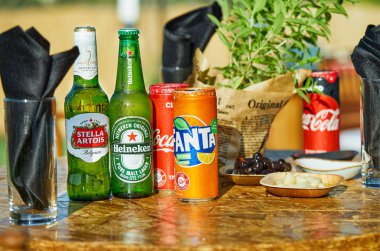 Tel Aviv, İsrail - 17 Temmuz 2020: Heineken, Stella Artois, Coca-Cola ve Fanta şişeleri açık hava masasında abur cubur ve peçetelerle sergileniyor.