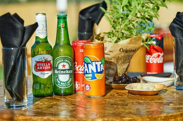 Tel Aviv, İsrail - 17 Temmuz 2020: Heineken, Stella Artois, Coca-Cola ve Fanta şişeleri açık hava masasında abur cubur ve peçetelerle sergileniyor.