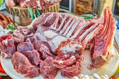 A variety of raw meat cuts, including ribs and tenderloin, displayed on a wooden board, ready for preparation and cooking. clipart