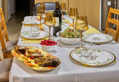 Şenlikli bir yemek için zarif bir yemek masası, şarap kadehleri, tabaklar ve canlı bir salata süsü..