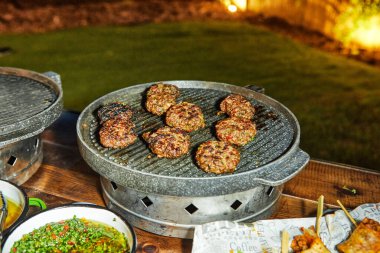 Perfectly grilled beef patties sizzling on an outdoor iron grill, showcasing a deliciously charred exterior for a cookout. clipart