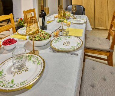 Şenlikli bir yemek için zarif bir yemek masası, şarap kadehleri, tabaklar ve canlı bir salata süsü..