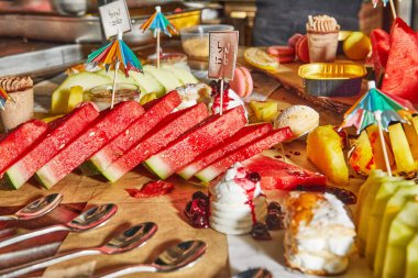 İçinde karpuz, ananas, tatlı ve küçük dekoratif şemsiyeler bulunan renkli bir meyve tabağı ferahlatıcı bir yaz ziyafeti için mükemmel. İbranice yazılar. Tebrikler..