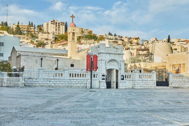 Nasıra, İsrail - 15 Şubat 2025: Tarihi bir kilise ve dini kompleksin panoramik görüntüsü, geleneksel mimarisi olan bir yamaç kentine karşı kurulmuştur..