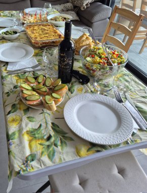 Hayfa, İsrail 1 Haziran 2025: Çeşitli salatalar, aperatifler, şarap ve sıcak bir ev yemeği ya da kutlama yemeği için hazır fırınlanmış yemeklerle dolu şenlikli bir yemek masası.