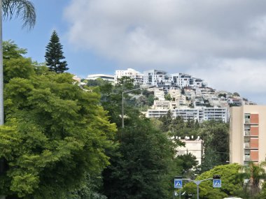 Yeşillik ve tropikal ağaçlar tepedeki beyaz binalarla çelişiyor ve mavi gökyüzünün altında huzurlu bir yerleşim alanı yaratıyor..