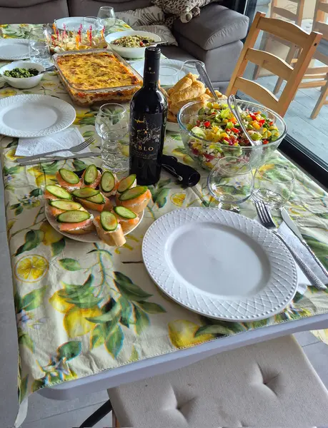 Hayfa, İsrail 1 Haziran 2025: Çeşitli salatalar, aperatifler, şarap ve sıcak bir ev yemeği ya da kutlama yemeği için hazır fırınlanmış yemeklerle dolu şenlikli bir yemek masası.