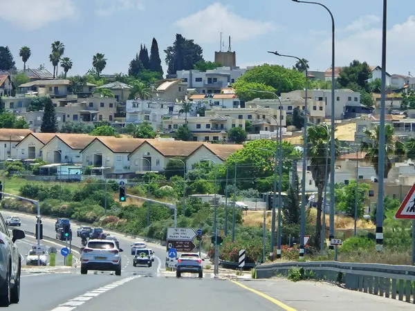 Hayfa, İsrail 24 Mayıs 2025: Çok şeritli bir otoyol, açık mavi gökyüzü altında elektrik direkleriyle ve yeşil manzaralarla çevrili olan mesafeye uzanıyor.