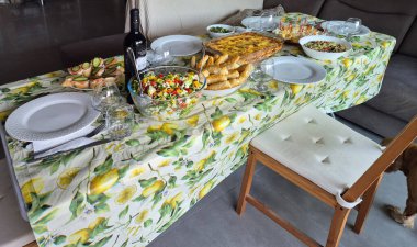 Hayfa, İsrail 1 Haziran 2025: Çeşitli salatalar, aperatifler, şarap ve sıcak bir ev yemeği ya da kutlama yemeği için hazır fırınlanmış yemeklerle dolu şenlikli bir yemek masası.