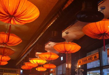 Hayfa, İsrail 30 Mayıs 2025: Parlak turuncu tavan lambaları Asya temalı bir restoranda sıcak ışıklandırma ve kültürel tasarım referanslarıyla sanatsal bir kompozisyon oluşturur.