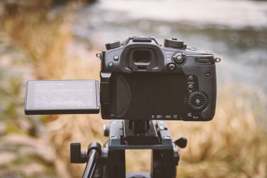 Open back of camera filming water with yellow reeds and garass landscape with visible menu on the turned screen