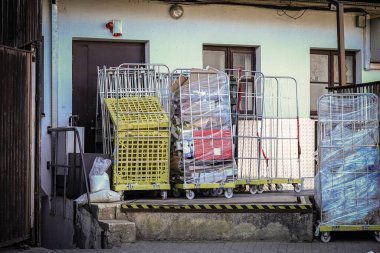 Camların önündeki bir mağazanın önünde plastik ambalaja sarılı yüksek kablolu çöp konteynırları.