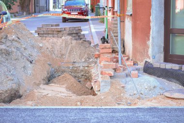 Yol onarımı ve dikkat kırmızı tuğlalar yoldaki deliğin yanında yığılı ve bir sürü kum