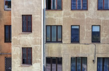 Merdiven çeliği su borusuyla kahverengi bina duvarı ve binanın içinde çeşitli nesneler ve insanlar olan birçok farklı pencere.