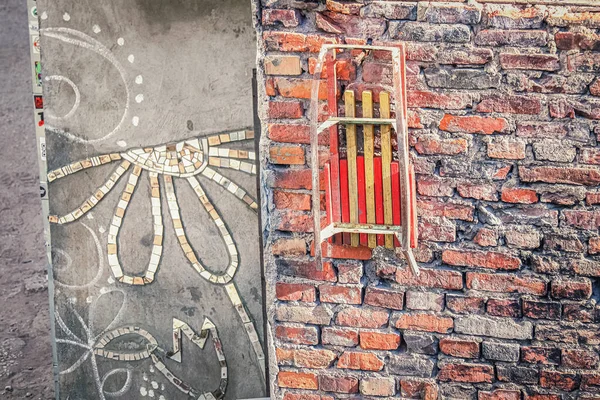 Gammal Släde Hängande Röd Tegelvägg Byggnad Med Blommig Mosaik Konst — Stockfoto