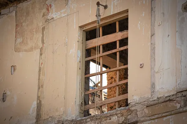 在废弃的老房子外面有金属网的旧窗户 在同一房间对面的墙上有明显的开着的窗户 — 图库照片