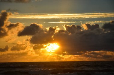 Güzel turuncu ve siyah desenli bulutlu gün batımı yaz mevsiminde Baltık deniz dalgalarında parlak güneş manzaralı.