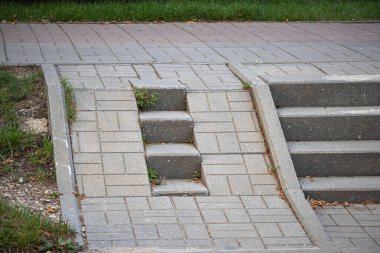 Gri tuğlalar, tekerlekli sandalye ya da bebek arabası için yeri olan merdiven kılıfı.