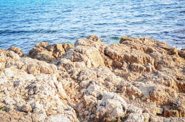 Dev kahverengi kaya desenli yamaç, güneşli bir günde deniz dalgaları üzerinde izole edilmiş..