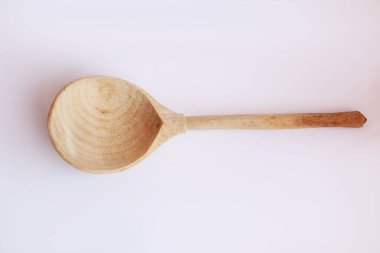 Tahta kaşık güneş ışığında beyaz arkaplanda izole edilmiş.