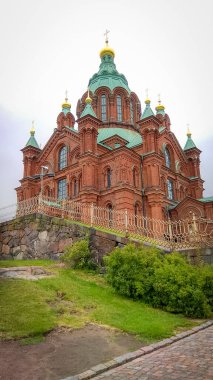 Helsinki 'deki Uspensky Katedrali - yol bulutlu bir günde yeşil mavi çatılı kırmızı tuğla kilise