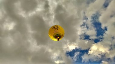 04 June 2020, Vilnius, Lithuania - Yellow Gariunai Hot Air Balloon flying up in the cloudy blue sky bottom up view clipart