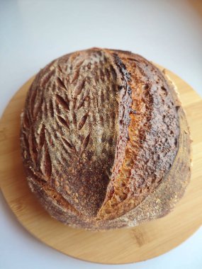 Ahşap bir yüzey manzarası üzerinde soğuyan kahverengi kabuklu taze pişmiş ekşi ekmek.