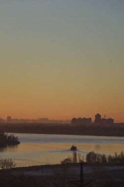 Şehrin üzerinde gün doğumu ya da batımı, Kyiv, Vyshhorod, Ukrayna, Dnipro Nehri 'nin kıvrımları gökyüzünü yansıtır, arkasında büyük bir şehir vardır. Sarı gökyüzü, açık sis. Arka planın güzel bir resmi..