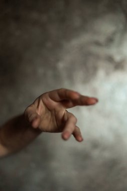 Gri arkaplanlı, seçici odaklı, basit bir manikürlü, güzel bir kadın elinin yakın çekimi. Uzun parmaklar ve narin bir bilek, plastik hareket.