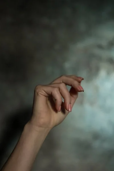 一只漂亮的女性手部的特写 指甲修剪简单 背景灰暗 重点突出 编织长手指和脆弱的腕部 塑形运动 — 图库照片