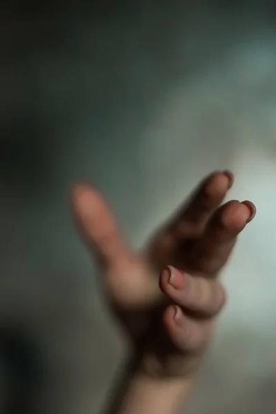 stock image Close-up of a beautiful female hand with a simple nail manicure, on a gray background, selective focus. Weave long fingers and a fragile wrist, plastic movement.