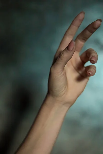 stock image Close-up of a beautiful female hand with a simple nail manicure, on a gray background, selective focus. Weave long fingers and a fragile wrist, plastic movement.