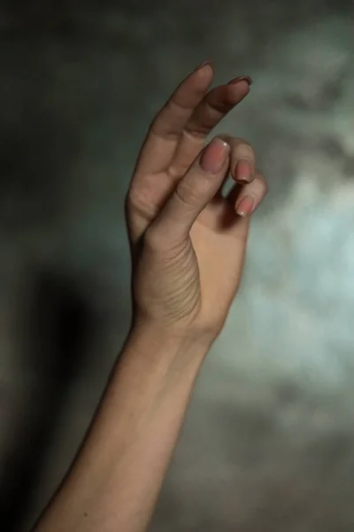 一只漂亮的女性手部的特写 指甲修剪简单 背景灰暗 重点突出 编织长手指和脆弱的腕部 塑形运动 — 图库照片#