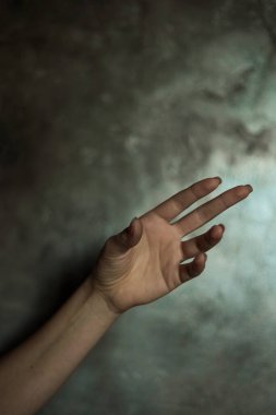 Gri arkaplanlı, seçici odaklı, basit bir manikürlü, güzel bir kadın elinin yakın çekimi. Uzun parmaklar ve narin bir bilek, plastik hareket.