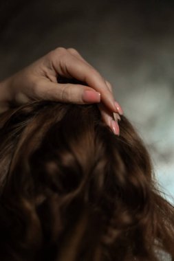 Gri arka planda basit tırnak manikürlü, seçici odaklı güzel kadın elinin yakın çekimi. Uzun parmaklar ve kırılgan bilekler, uzun kızıl saçların arka planında plastik hareketler..