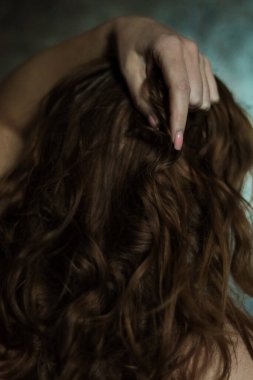 Gri arka planda basit tırnak manikürlü, seçici odaklı güzel kadın elinin yakın çekimi. Uzun parmaklar ve kırılgan bilekler, uzun kızıl saçların arka planında plastik hareketler..