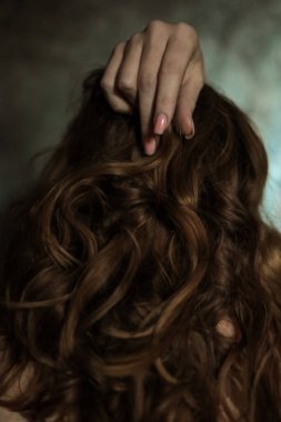 Gri arka planda basit tırnak manikürlü, seçici odaklı güzel kadın elinin yakın çekimi. Uzun parmaklar ve kırılgan bilekler, uzun kızıl saçların arka planında plastik hareketler..