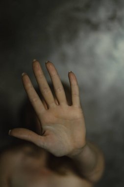 Gri duvar arkaplanına karşı korunmasız dişi poposu yakın plan, seçici odaklanma. Bir kadın ya kendini korur ya da saklanır. Şiddet ve koruma teması, kişisel sınırlar