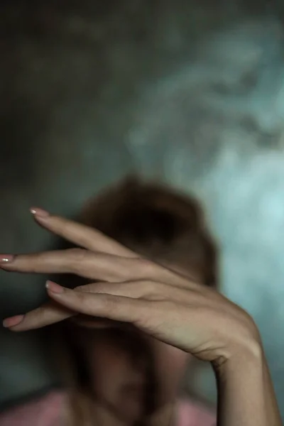 美丽的女性手部的特写 带有简单的指甲修剪 灰色背景 选择性聚焦 长长的手指和脆弱的手腕 面部和灰色墙壁后面的塑料动作 — 图库照片