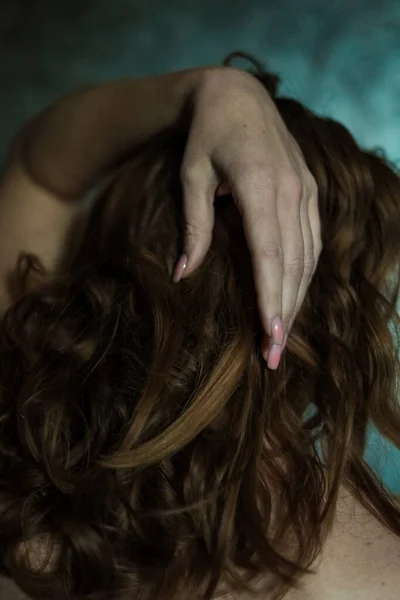グレーの背景にシンプルなネイルマニキュアで美しい女性の手のクローズアップ 選択的な焦点 長い指と壊れやすい手首 暗い長い赤い髪の背景にプラスチック製の動き — ストック写真