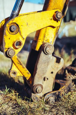 Parlak güneş ışığında inşaat alanında büyük kirli bir kovayla sarı bir traktörün yakın çekimi. ön görünüm