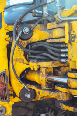 Büyük sarı bir traktörün parçası, yakın çekim, tüp ve bağlantı detayları. Parlak güneş ışığı, güzel teknik arkaplan