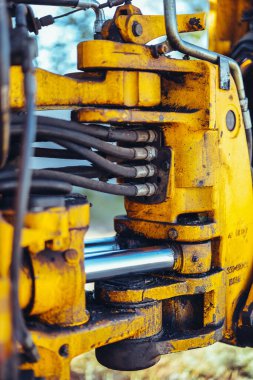 Büyük sarı bir traktörün parçası, yakın çekim, tüp ve bağlantı detayları. Parlak güneş ışığı, güzel teknik arkaplan