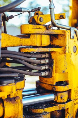 Büyük sarı bir traktörün parçası, yakın çekim, tüp ve bağlantı detayları. Parlak güneş ışığı, güzel teknik arkaplan