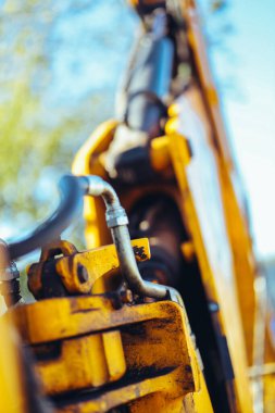 Büyük sarı bir traktörün parçası, yakın çekim, tüp ve bağlantı detayları. Parlak güneş ışığı, güzel teknik arkaplan