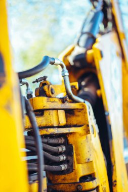 Büyük sarı bir traktörün parçası, yakın çekim, tüp ve bağlantı detayları. Parlak güneş ışığı, güzel teknik arkaplan