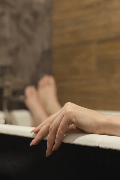 美丽的女性手手掌 有天然的修指甲在前景 腿在浴室 躺在放松 Spa的护肤程序快乐的女人美丽的背景 有选择的焦点 — 图库照片
