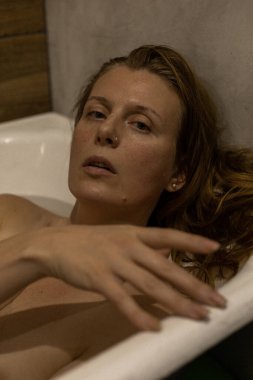 Küvette uzanıp güzellik ayininin tadını çıkaran mutlu bir kadın. Güzel bir kadın banyoda, sıcak suda dinleniyor. Temizlik, ev güzellik tedavileri, güzel bir geçmiş, seçici odaklanma..