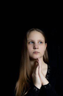 Uzun sarı saçlı, güzel, beyaz bir kızın ellerinin olduğu bir portre. Siyah arka planda doğal saçlı çocuklar.